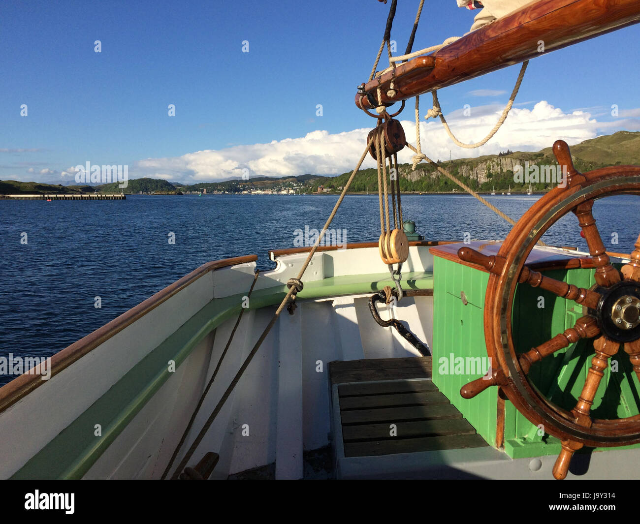 View from the stern of an old sailing ship taken from the Sound of Kerrara looking towards Oban in Scotland on a Spring evening Stock Photo
