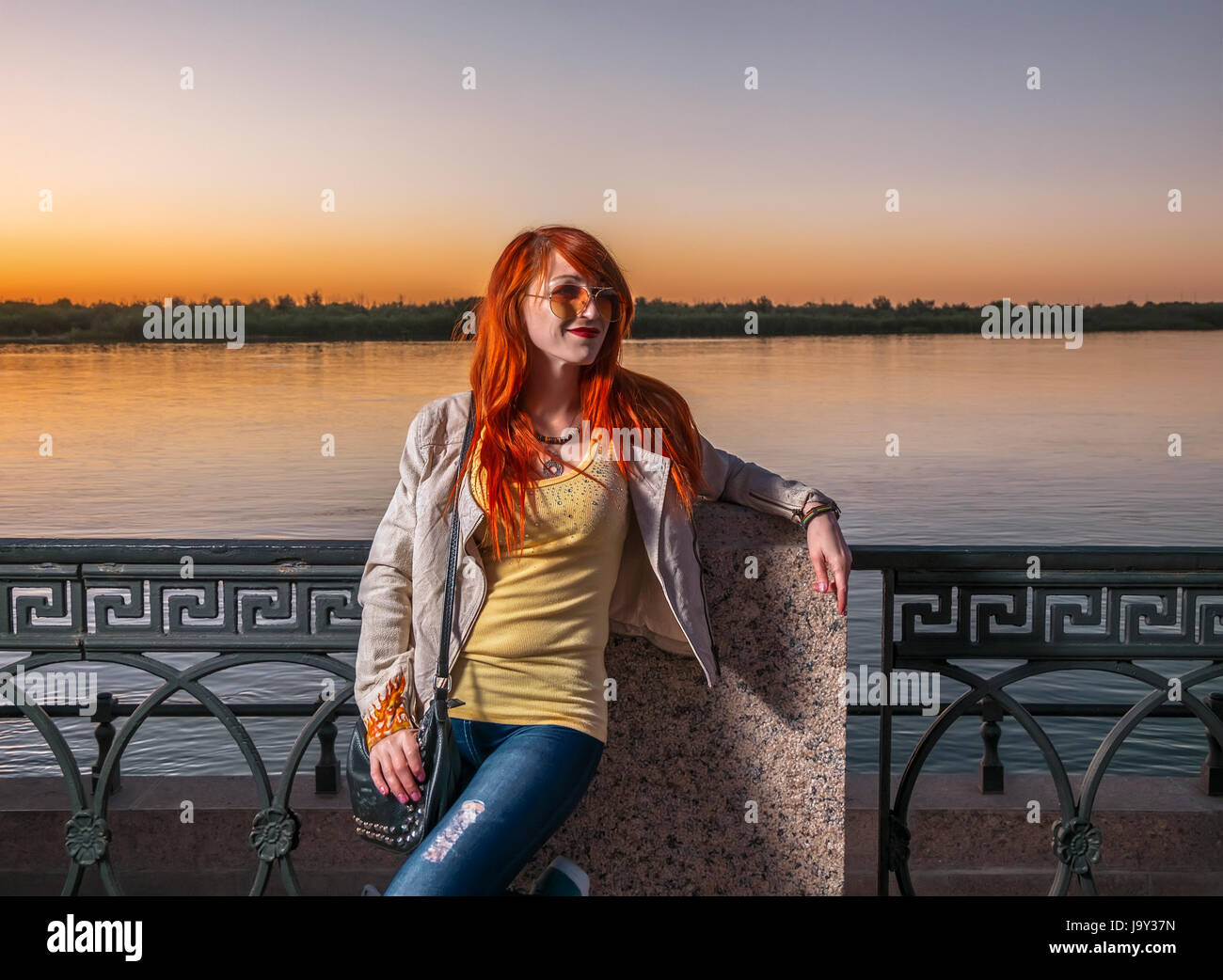 ginger head woman posing in sunglasses on river embankment, image with copy space Stock Photo