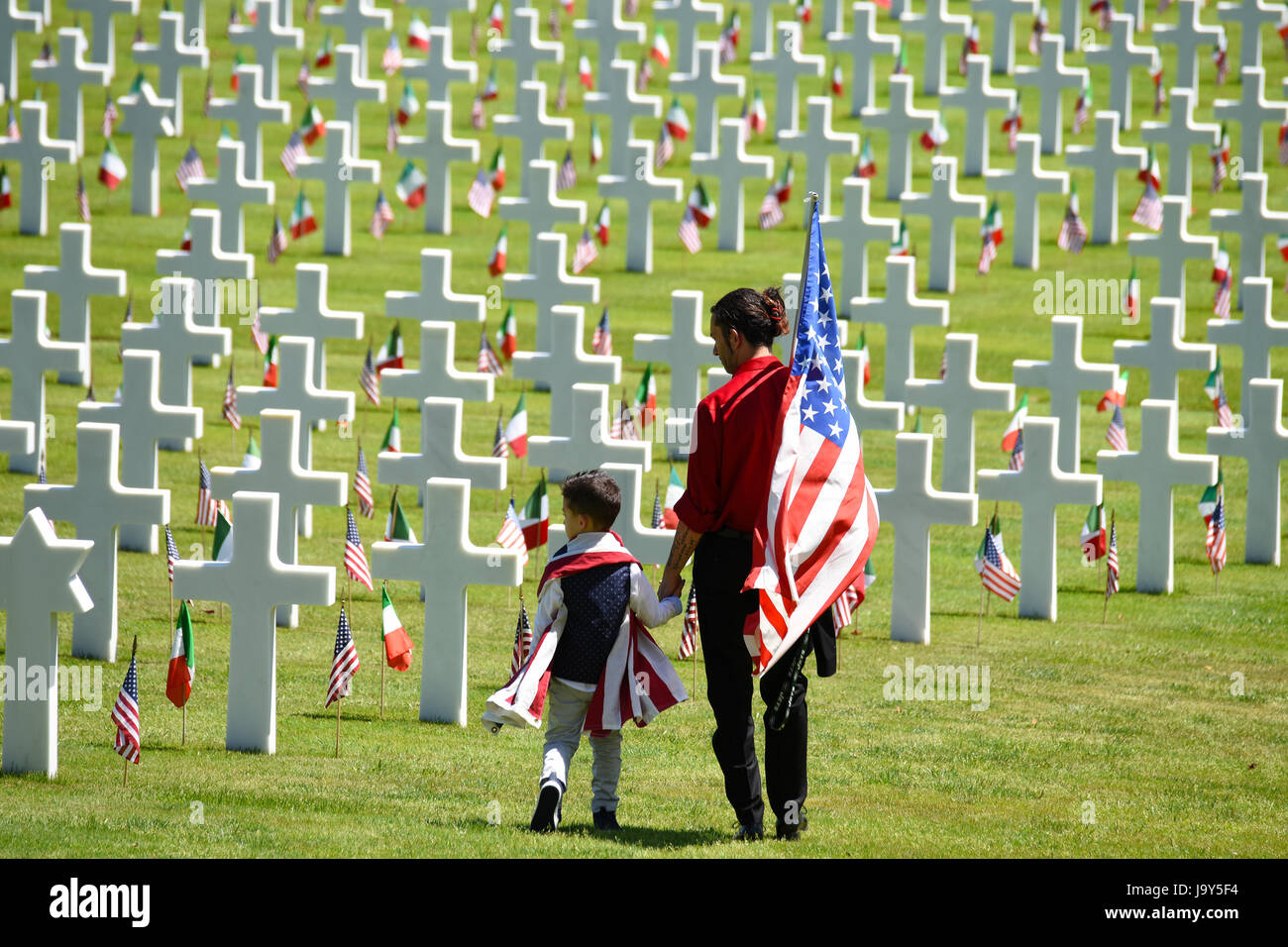 Family members pay their respects as they walk by the headstones of fallen soldiers during the Memorial Day ceremony at the Florence American Cemetery and Memorial May 29, 2017 in Florence, Italy.    (photo by Paolo Bovo /US Army  via Planetpix) Stock Photo