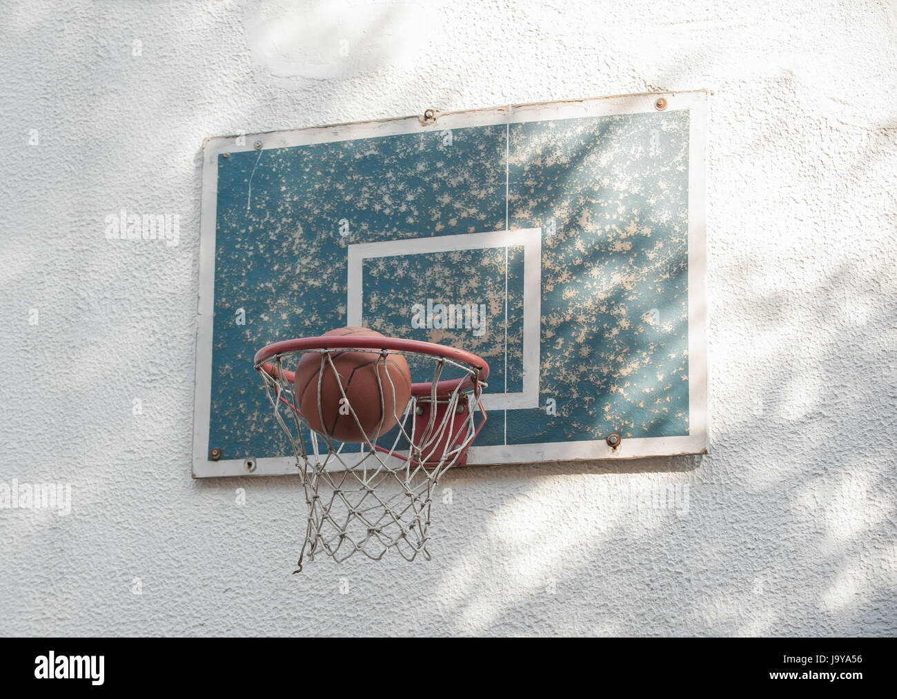 Ball basketball going through a small rustic old hoop with backboard on