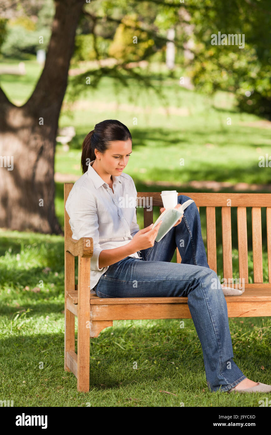 Young woman reading on the bench in a park Stock Photo - Alamy