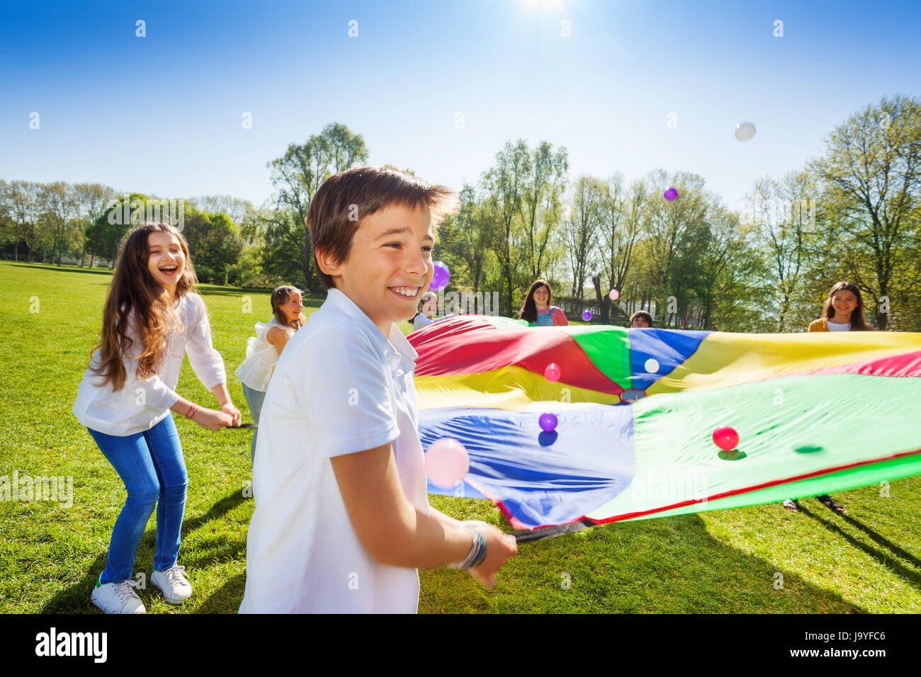 Boy throwing balls up by using rainbow parachute Stock Photo - Alamy