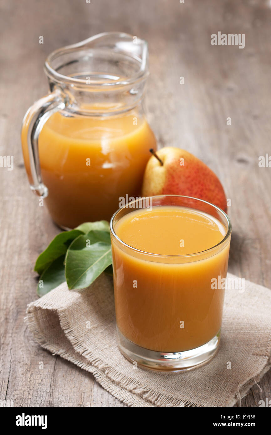 Pear juice in a glass beaker and jug, fresh pears on an old wooden
