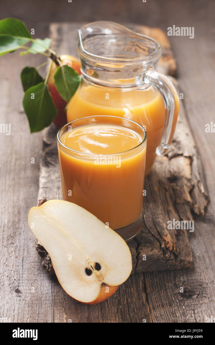 Pear juice in a glass beaker and jug, fresh pears on an old wooden ...