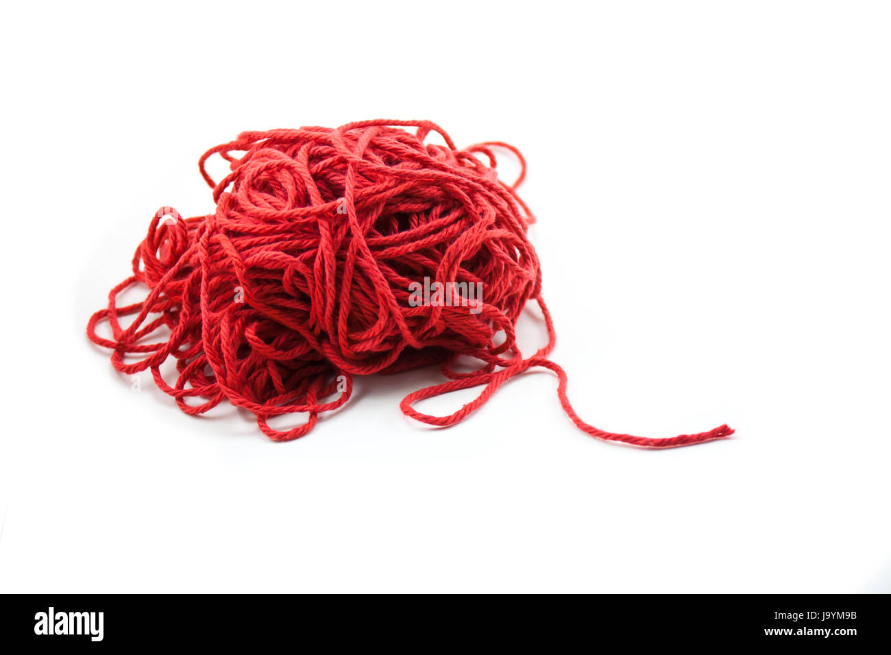 Tangled pile of red yarn with a single piece leading out, isolated on white. Stock Photo