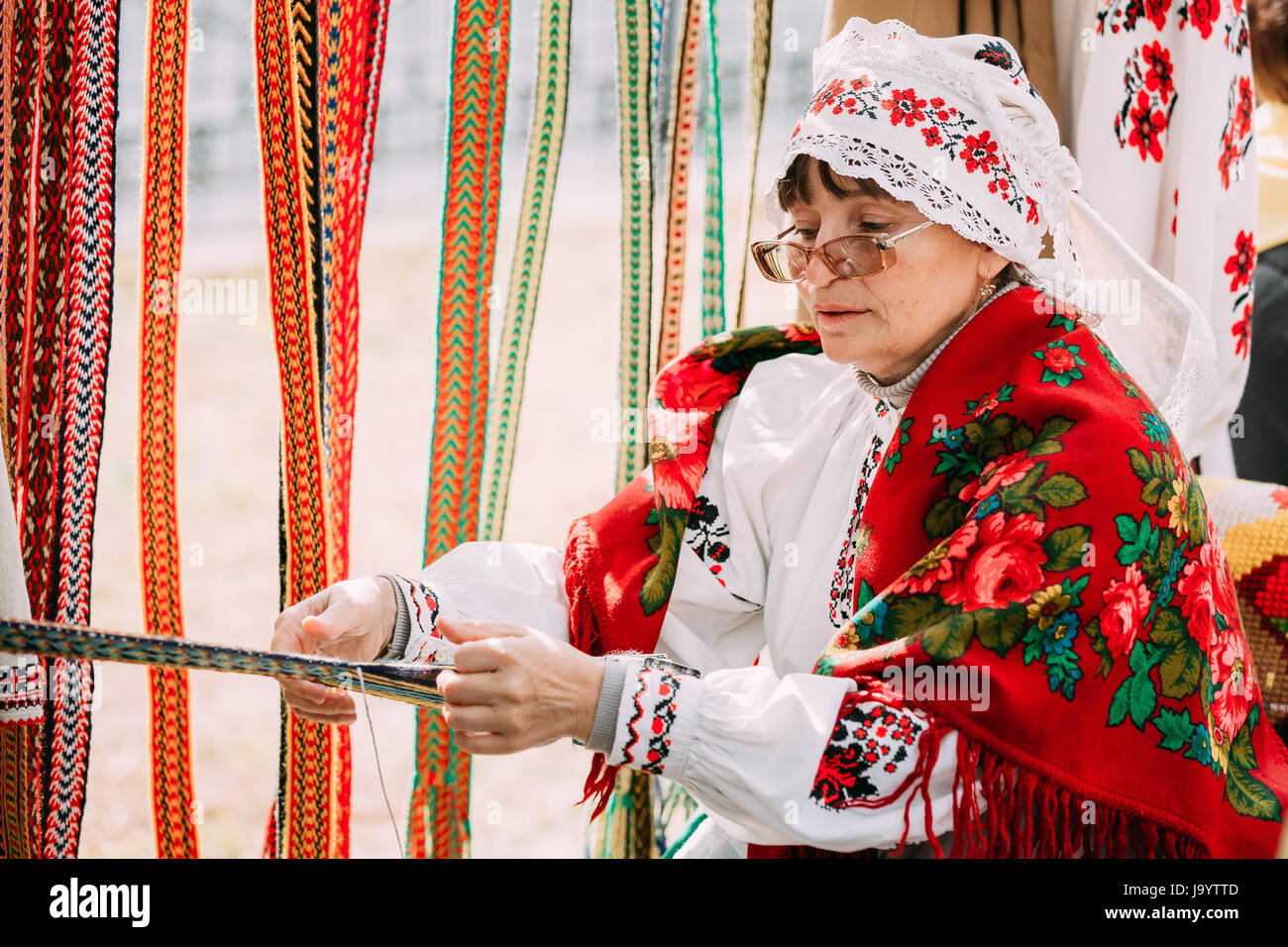 Gomel, Belarus - September 12, 2015: Woman in national Belarusian folk costume weaving belt Stock Photo