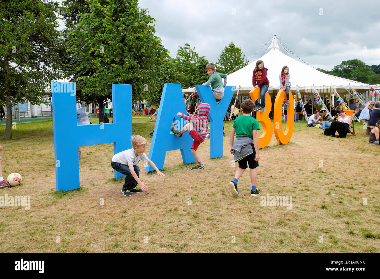 Kids playing outside climbing on the Hay 30 sign celebrating the 30th year of the Hay Festival, Hay-on-Wye, Wales UK    KATHY DEWITT Stock Photo