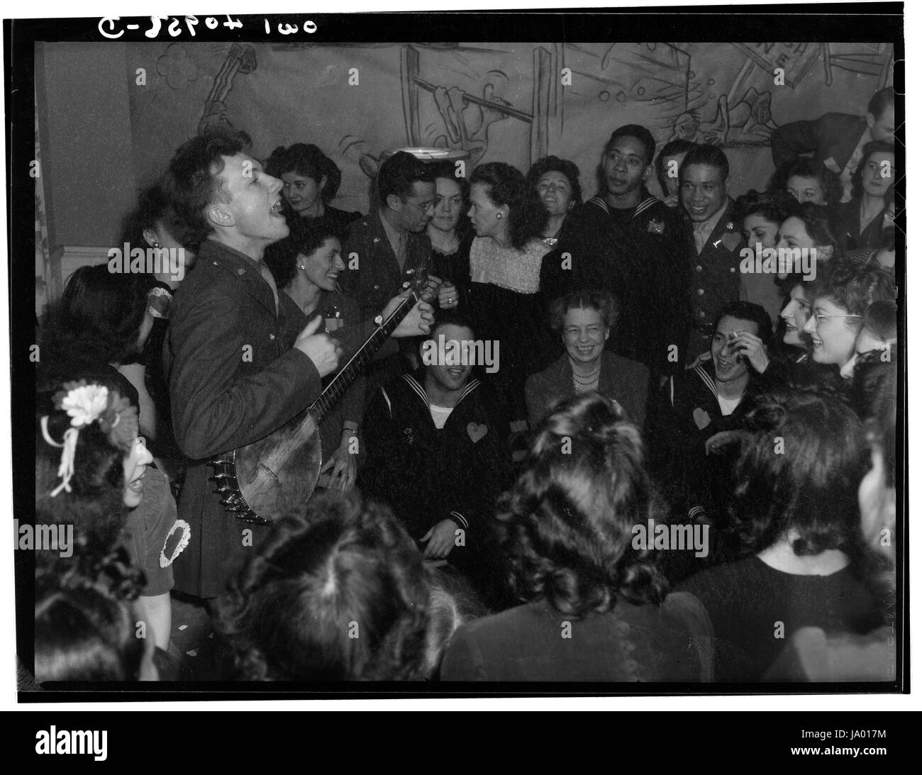 Folk Singer Pete Seeger (standing left) entertains First Lady Eleanor Roosevelt and others at the opening of the Washington, DC Federal Labor Canteen, Washington, DC, 02/1944. Stock Photo