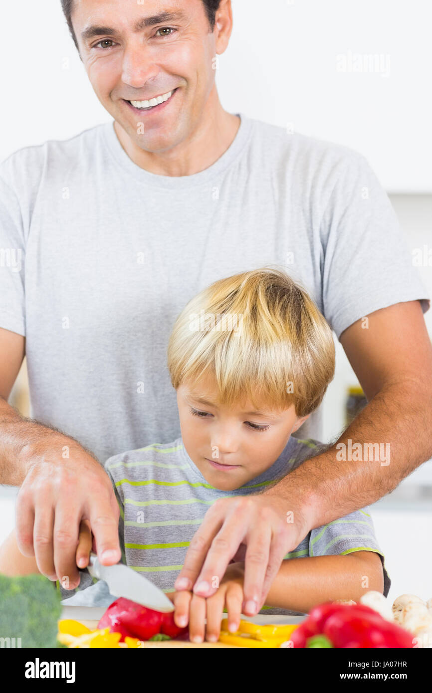 Father helping son to slice vegetables in the kitchen Stock Photo - Alamy