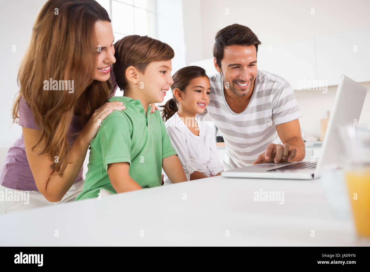 Happy family using a laptop in kitchen Stock Photo - Alamy