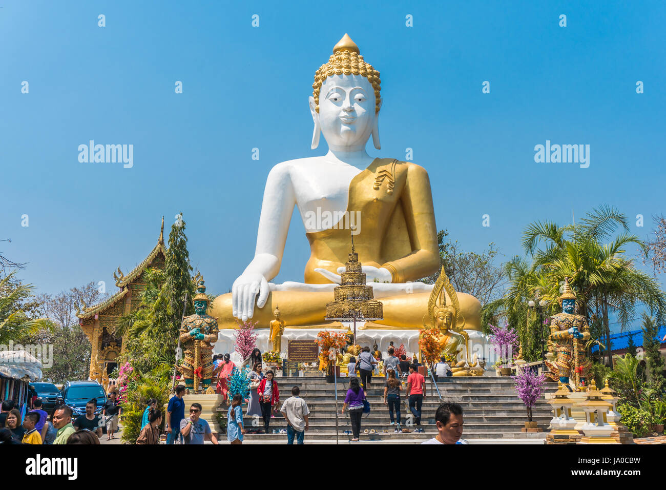 CHIANG MAI, THAILAND - MARCH 5, 2017: Thai pilgrims worship and tourist in the big sitting Buddha statue at Wat Phra That Doi Kham. It is a landmark i Stock Photo