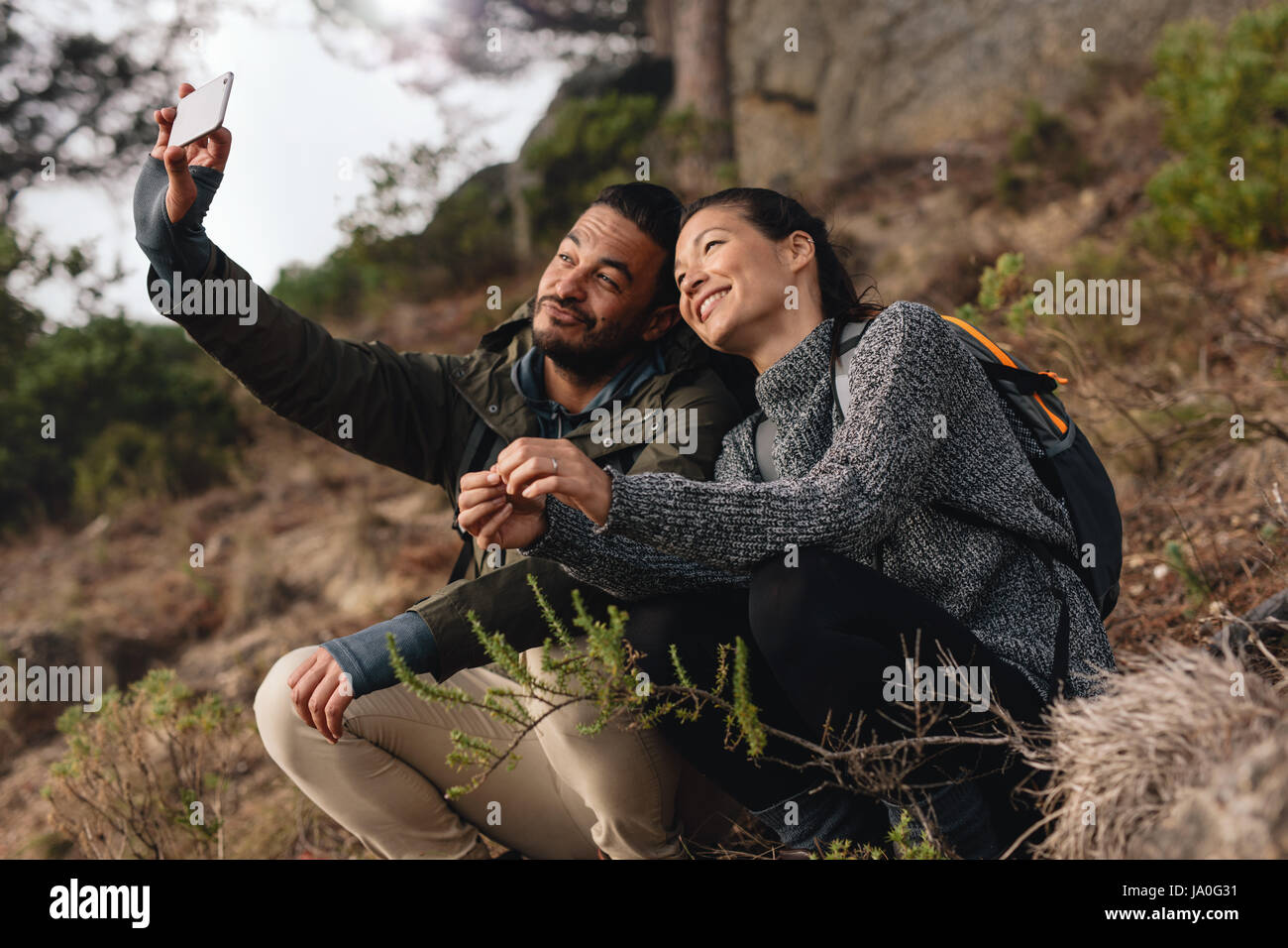 Young couple out on hike in mountains taking selfie with smart phone ...