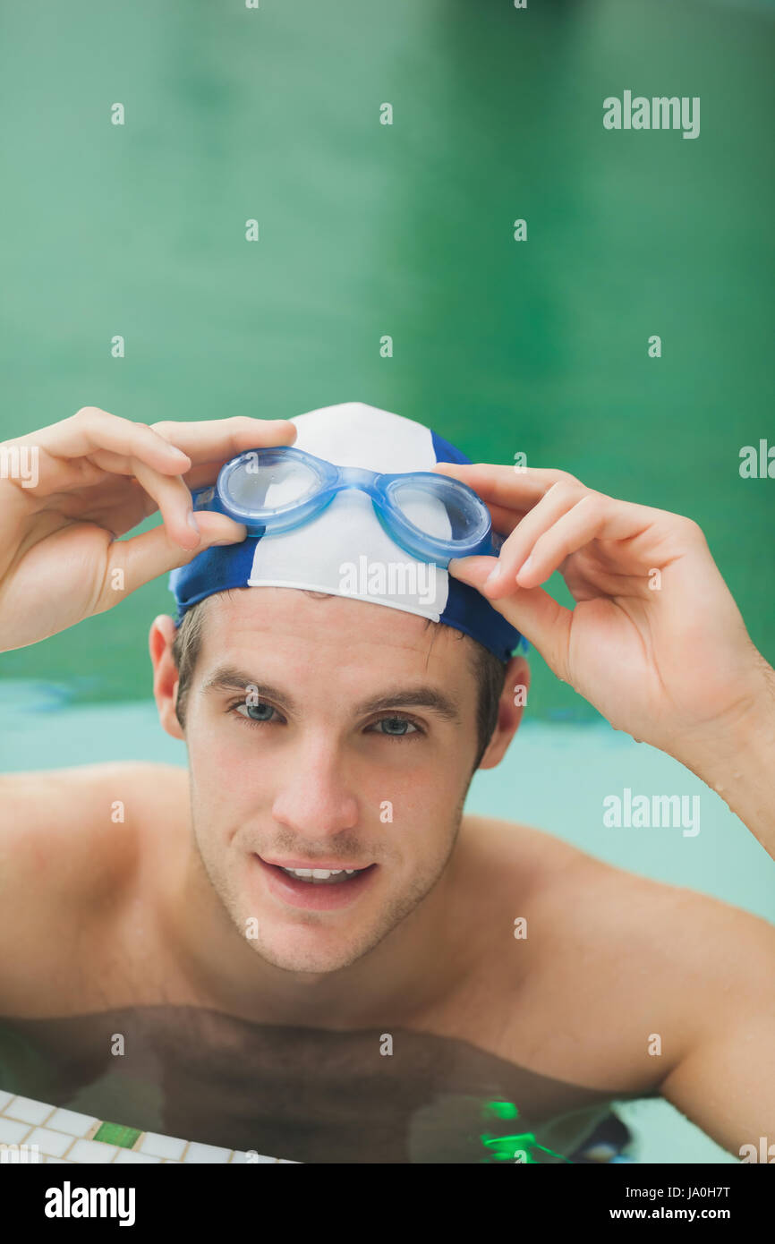 Smiling man taking off goggles in the swimming pool Stock Photo