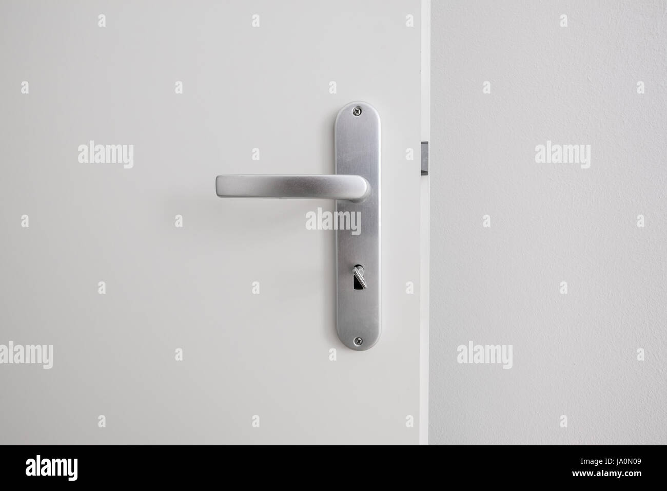 door handle with key on white door closeup Stock Photo
