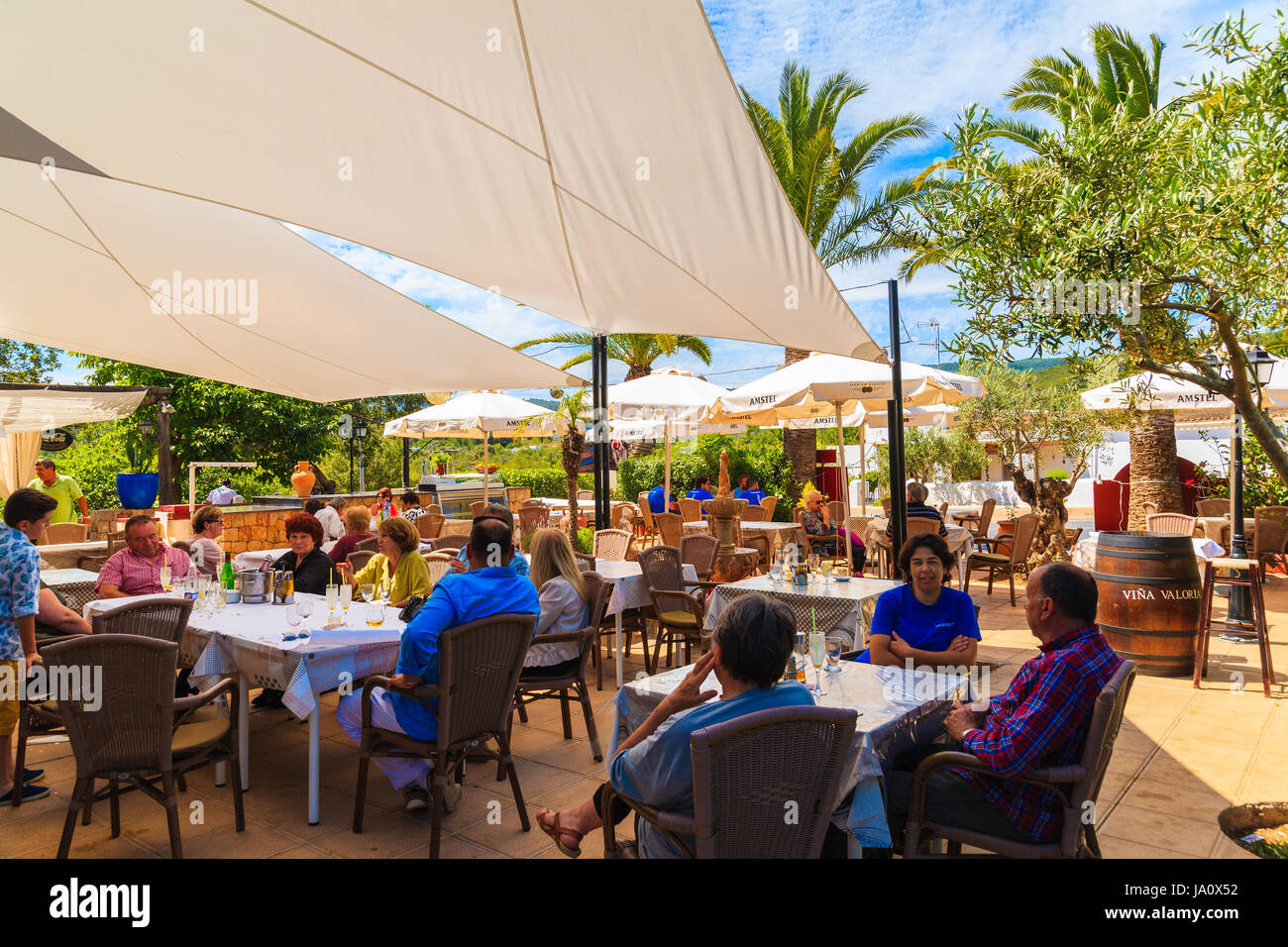 IBIZA ISLAND, SPAIN - MAY 18, 2017: people dining in garden of traditional restaurant on sunny summer day in Sant Carles de Peralta village, Ibiza isl Stock Photo