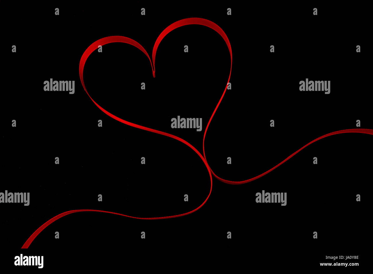 Red ribbon in heart shape on black background Stock Photo - Alamy