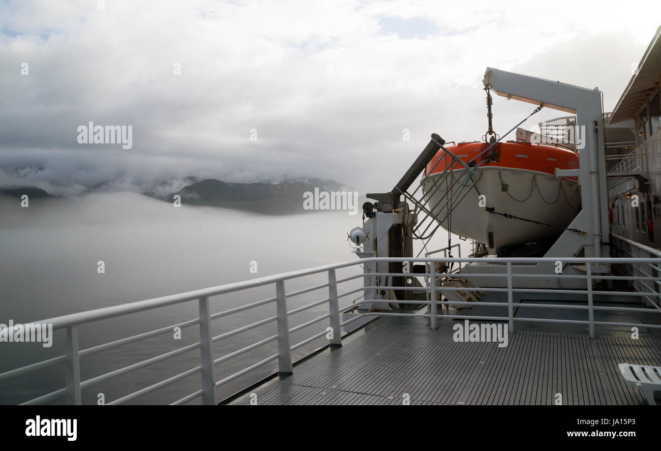 A sealed orange liefboat survival vessel is mounted on a larger ship Stock Photo
