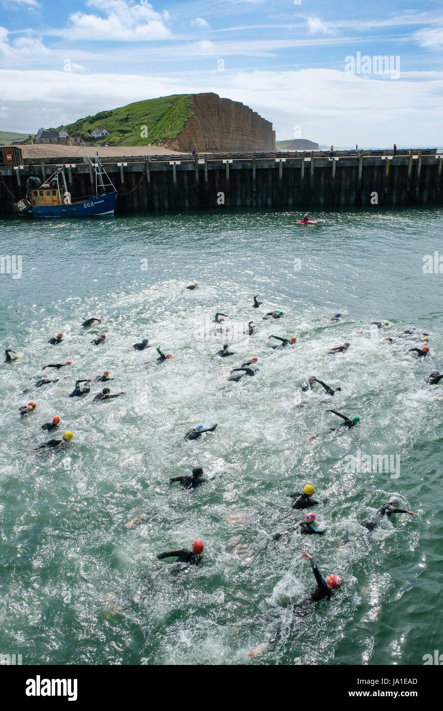 West Bay, Dorset, UK. 4th June, 2017. Competitors swim out of West Bay Harbour on the first stage of the a West Bay Triathlon. After a sea swim along Dorset's Jurassic coast competitors take part in a bike sprint through the West Dorset countryside before completing the event with a run along the coastal path. Credit: Tom Corban/Alamy Live News Stock Photo