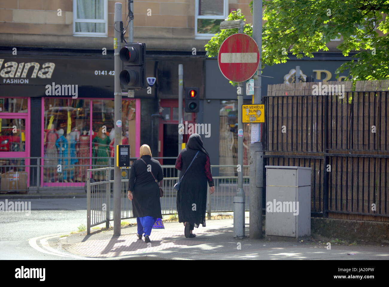 hijab scarf wearing Muslim on British street mo entry sign Stock Photo
