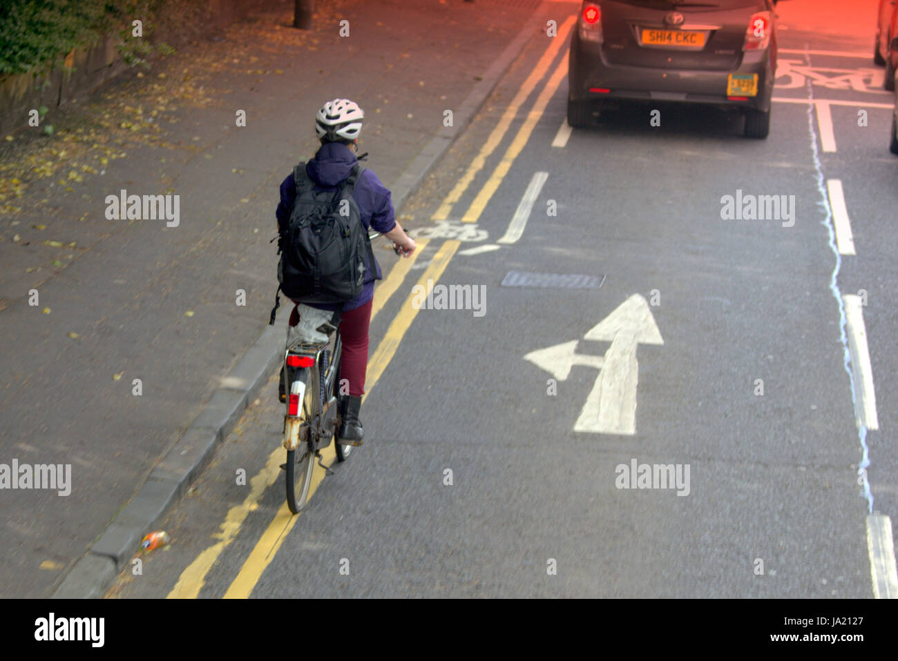 Young girl on bike cyclist in busy road traffic near bike lane and danger Stock Photo