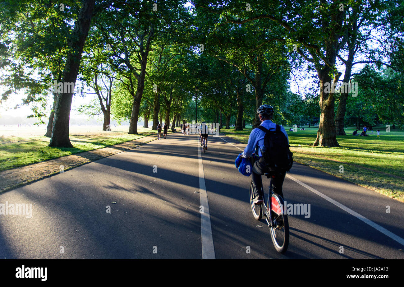 London, England - July 19, 2016: Cyclists riding 'Boris Bike' city hire bikes ride along the Broadwalk avenue in Hyde Park. Stock Photo