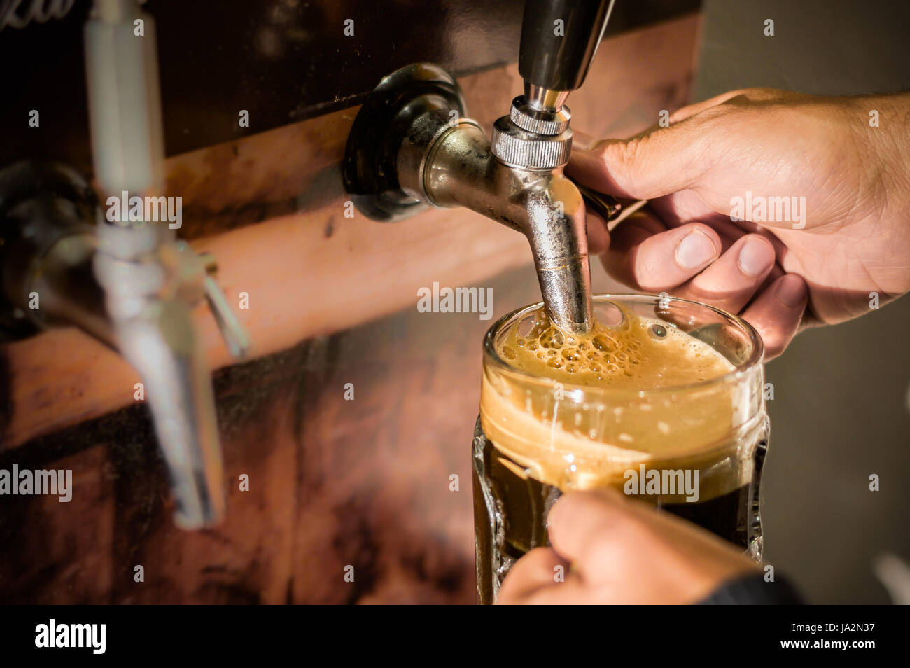 Bartender filling up with craft beer a pint glass Stock Photo