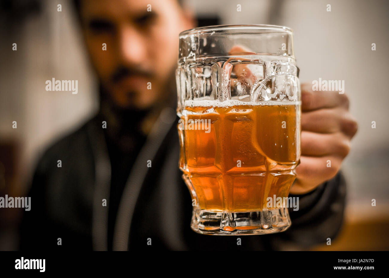 Bartender holdinga delicious blonde craft beer filled into a pint glass Stock Photo