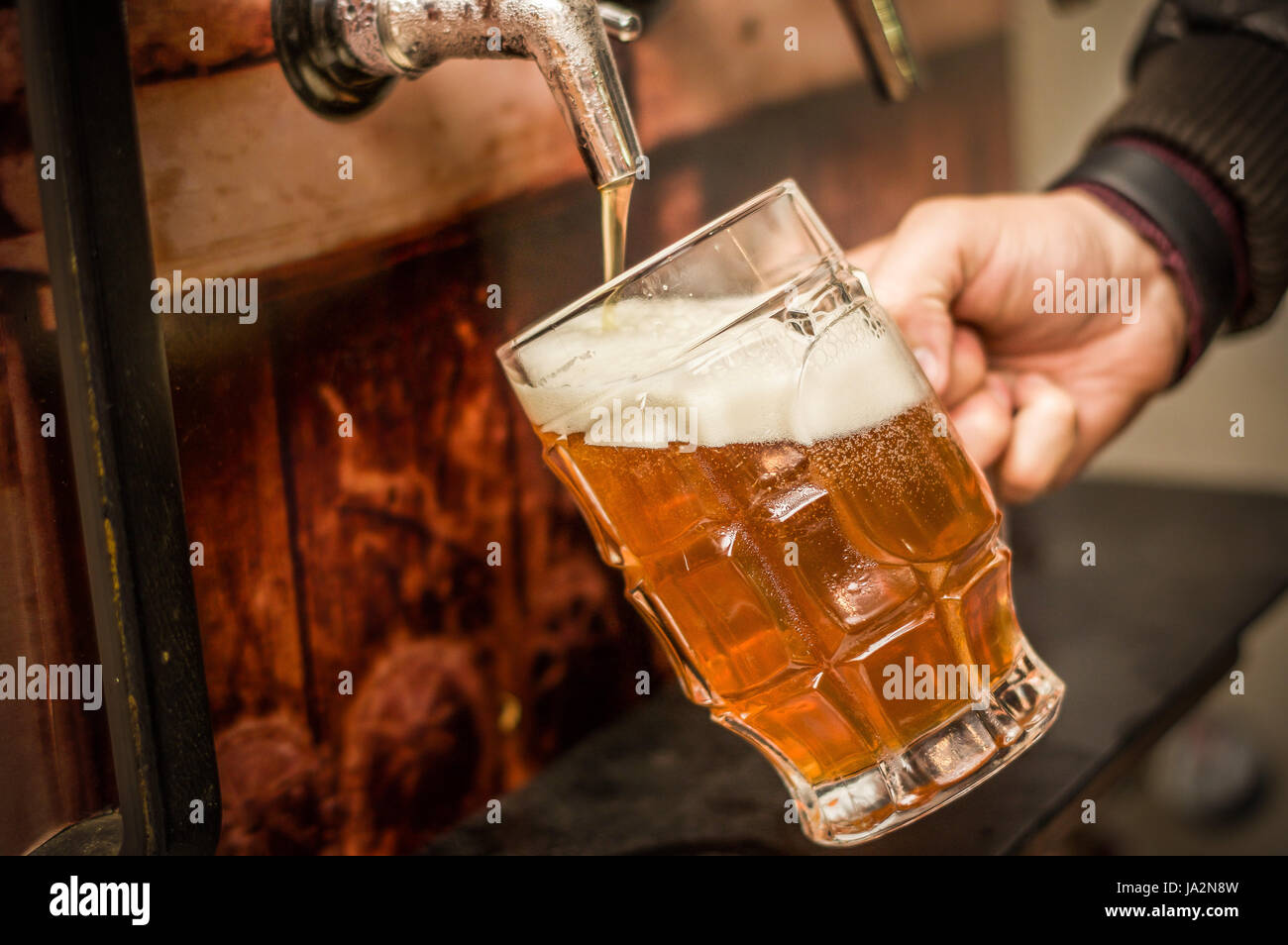 Bartender filling up with a blonde craft beer into a pint glass Stock Photo