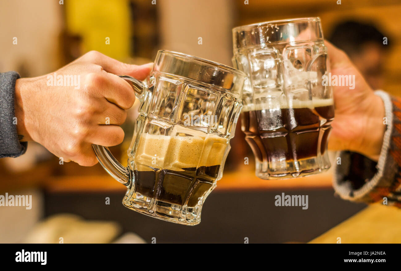 Happy male friends clinking with beer mugs in pub Stock Photo