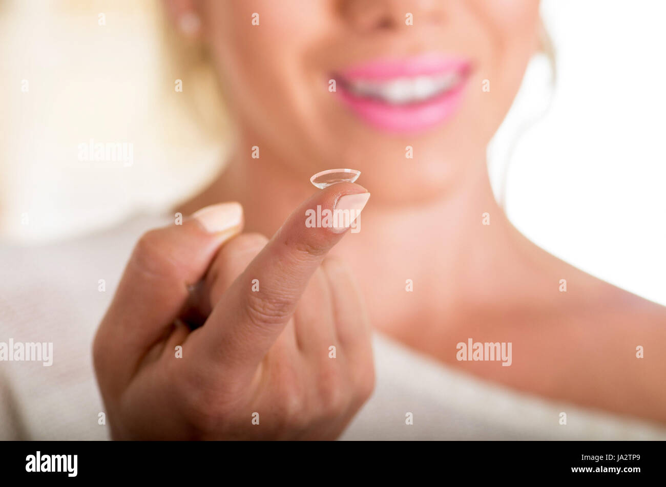 Young woman holding contact lens on finger in front of her face on white background., eyesight and eyecare concept Stock Photo