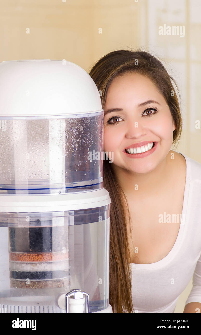 Beautiful woman next to the filter system of water purifier on a kitchen background Stock Photo