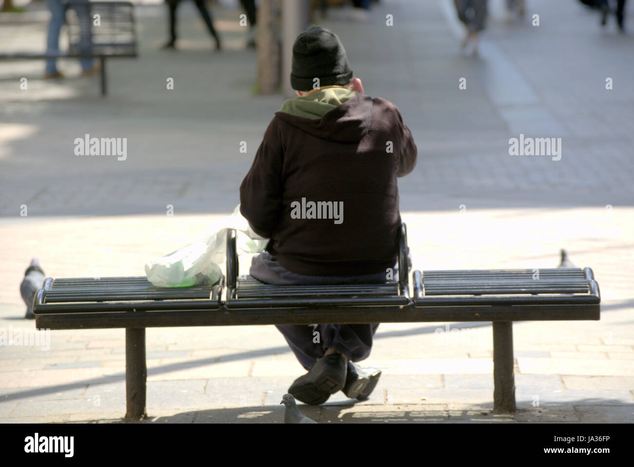 Sauchiehall Street sitting on a bench viewed from behind gnomish man on a mobile phone Stock Photo