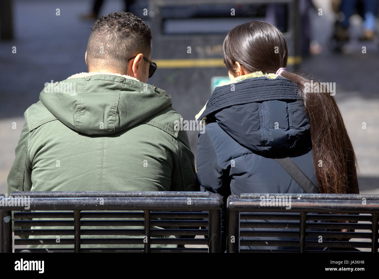 tourists on the streets of Glasgow Scotland sitting from behind Stock Photo