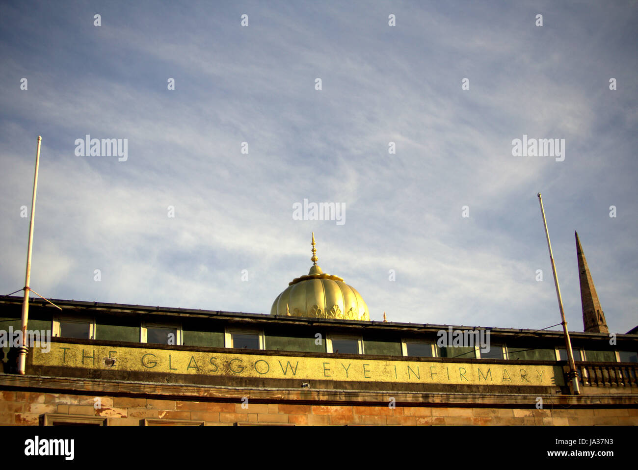old Glasgow eye infirmary gold frontage sign against the sky and church spire and  Gurdwara dome Stock Photo