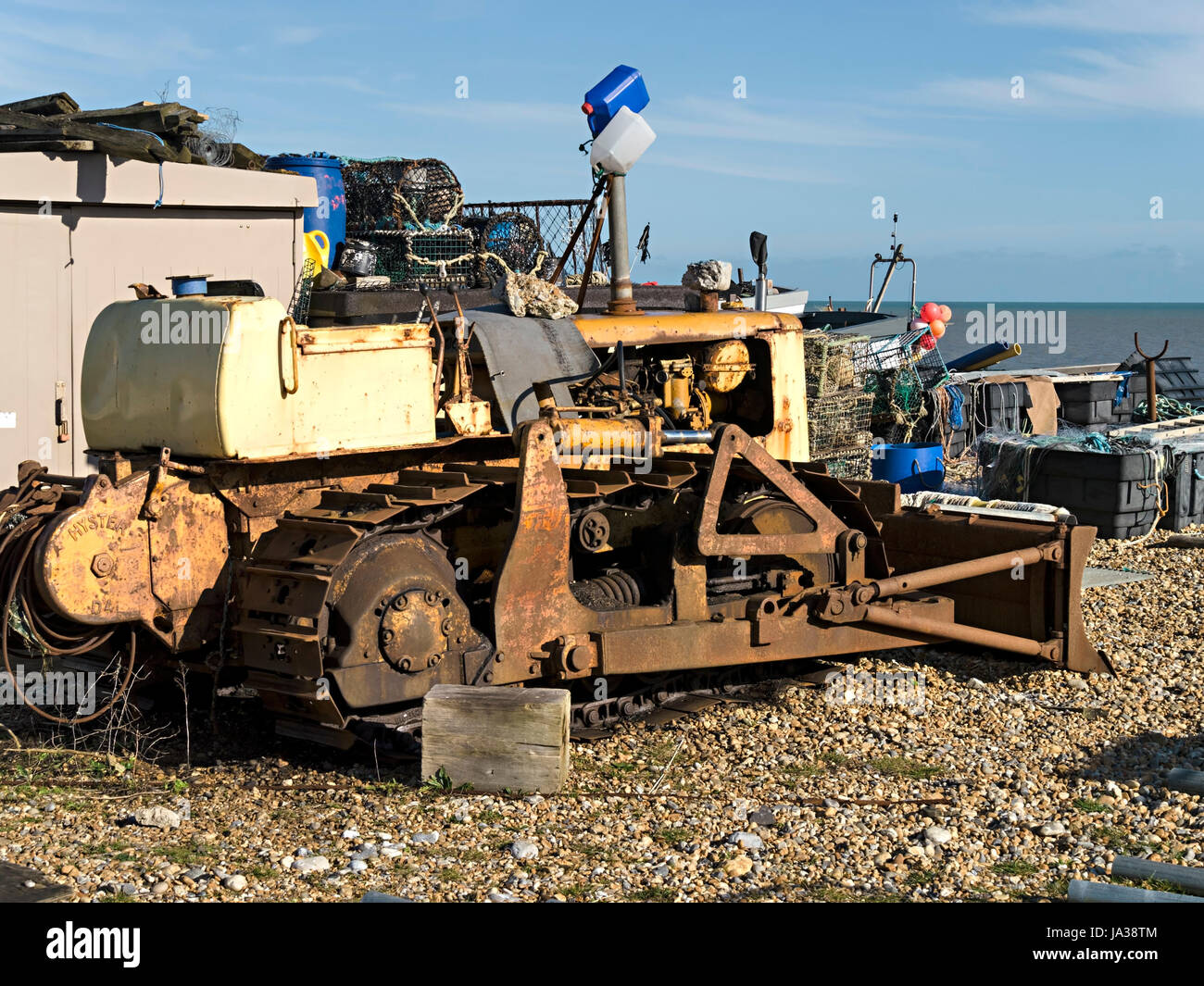 Old, rusty, yellow, Caterpillar tracked bulldozer used for launching and landing boats on Eastbourne shingle beach, Eastbourne, East Sussex, England. Stock Photo