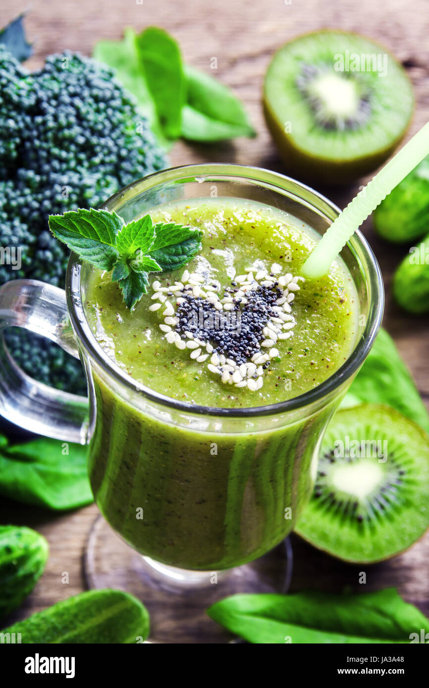 Green vegetable and herbs smoothie with heart of poppy and sesame seeds. Love healthy raw food concept. Stock Photo