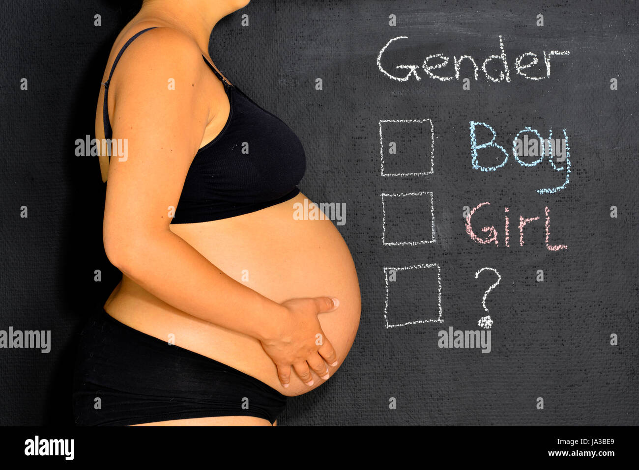 A pregnant lady standing next to a check sheet where you can check the gender of your child. Stock Photo