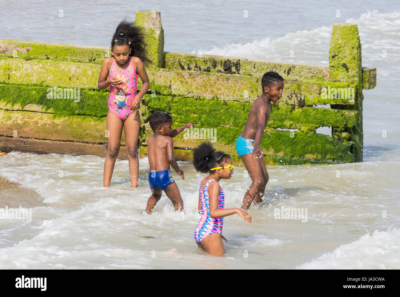 Black children at the seaside. A family of young black children playing in the sea in Summer in the UK. Stock Photo