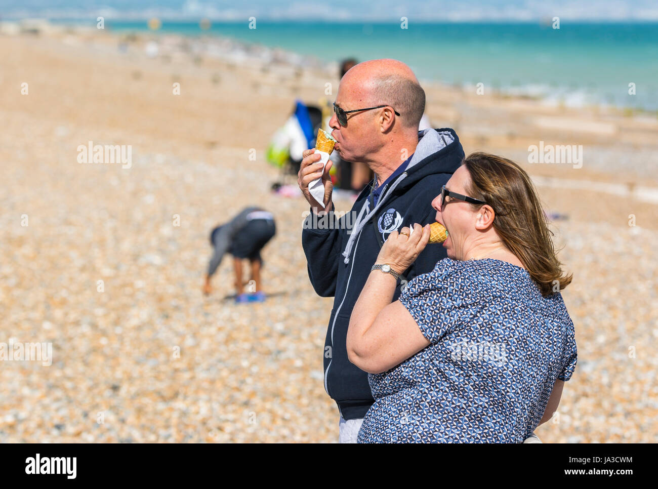 A couple eating ice cream on the beach in Summer in the UK. Stock Photo