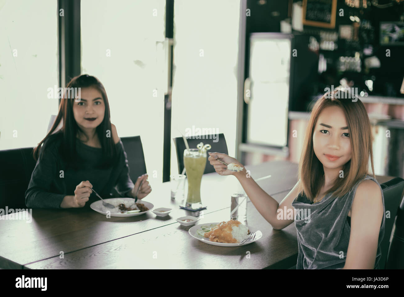 Two young female friends laugh and Having Lunch Together At Restaurant ...