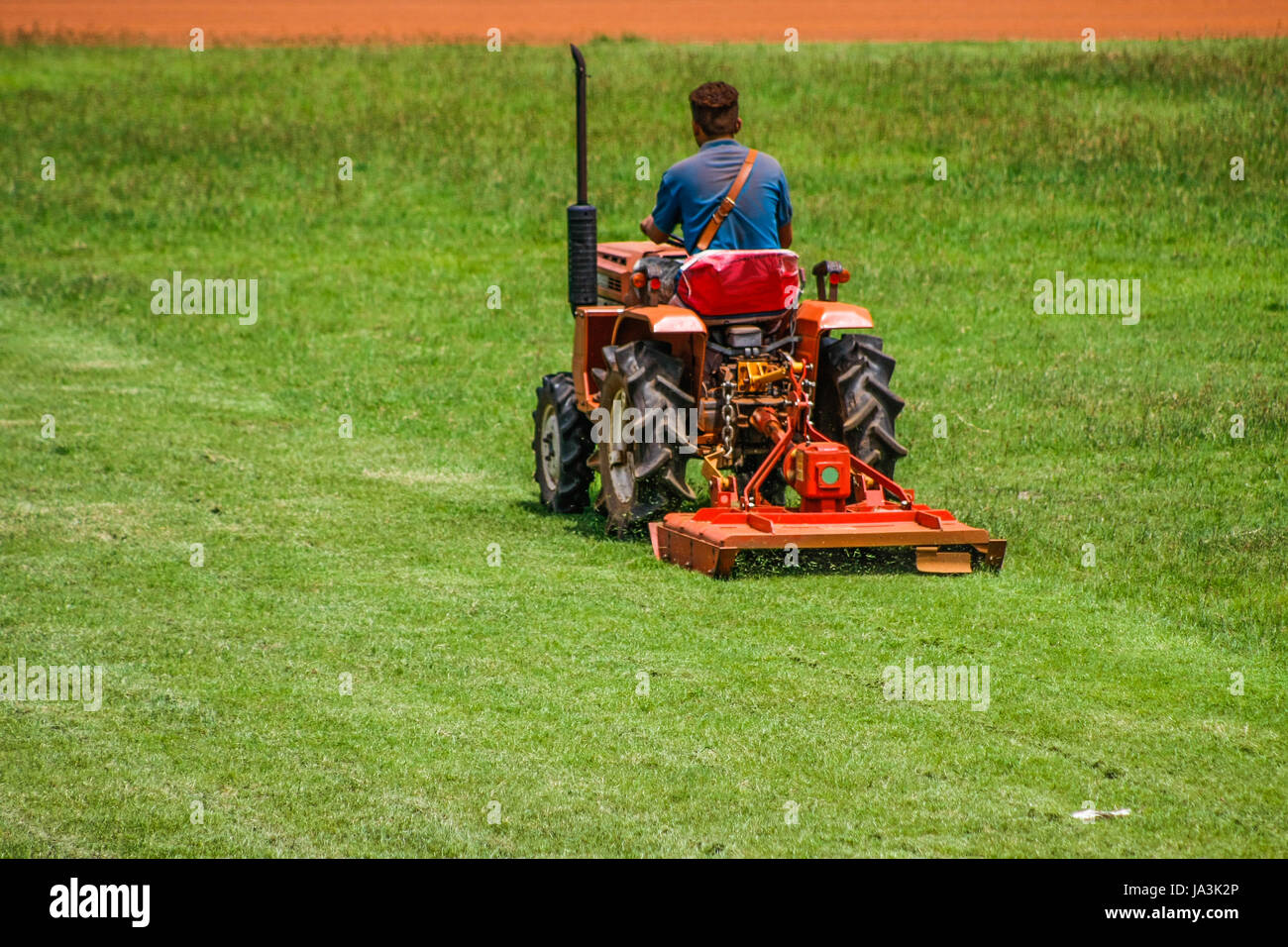a man on mower cutting grass in football field Stock Photo