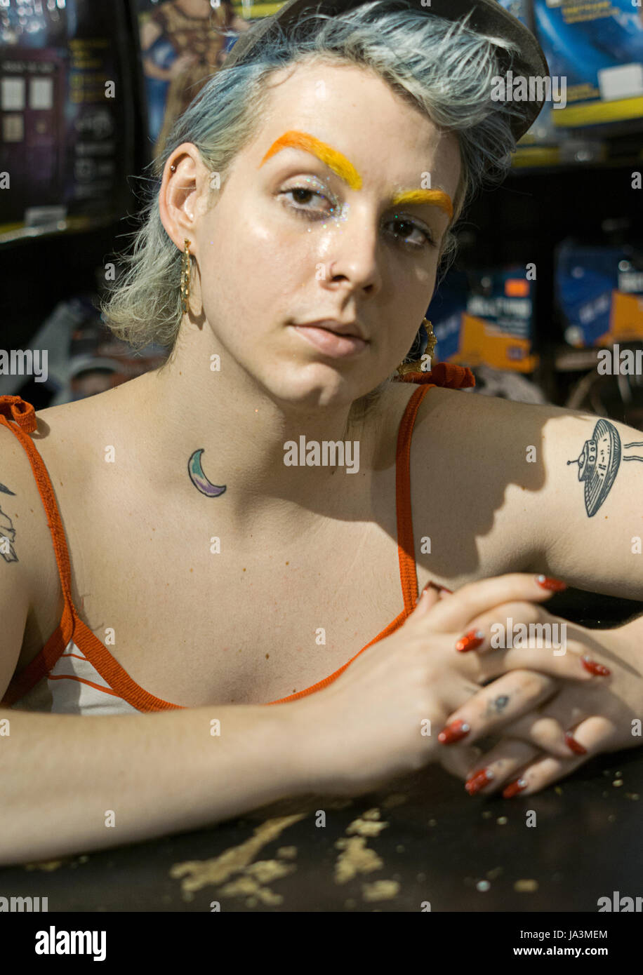 Posed portrait of a transitioning transgender woman with orange eyebrows blue hair and red nail polish. In Manhattan, New York City. Stock Photo