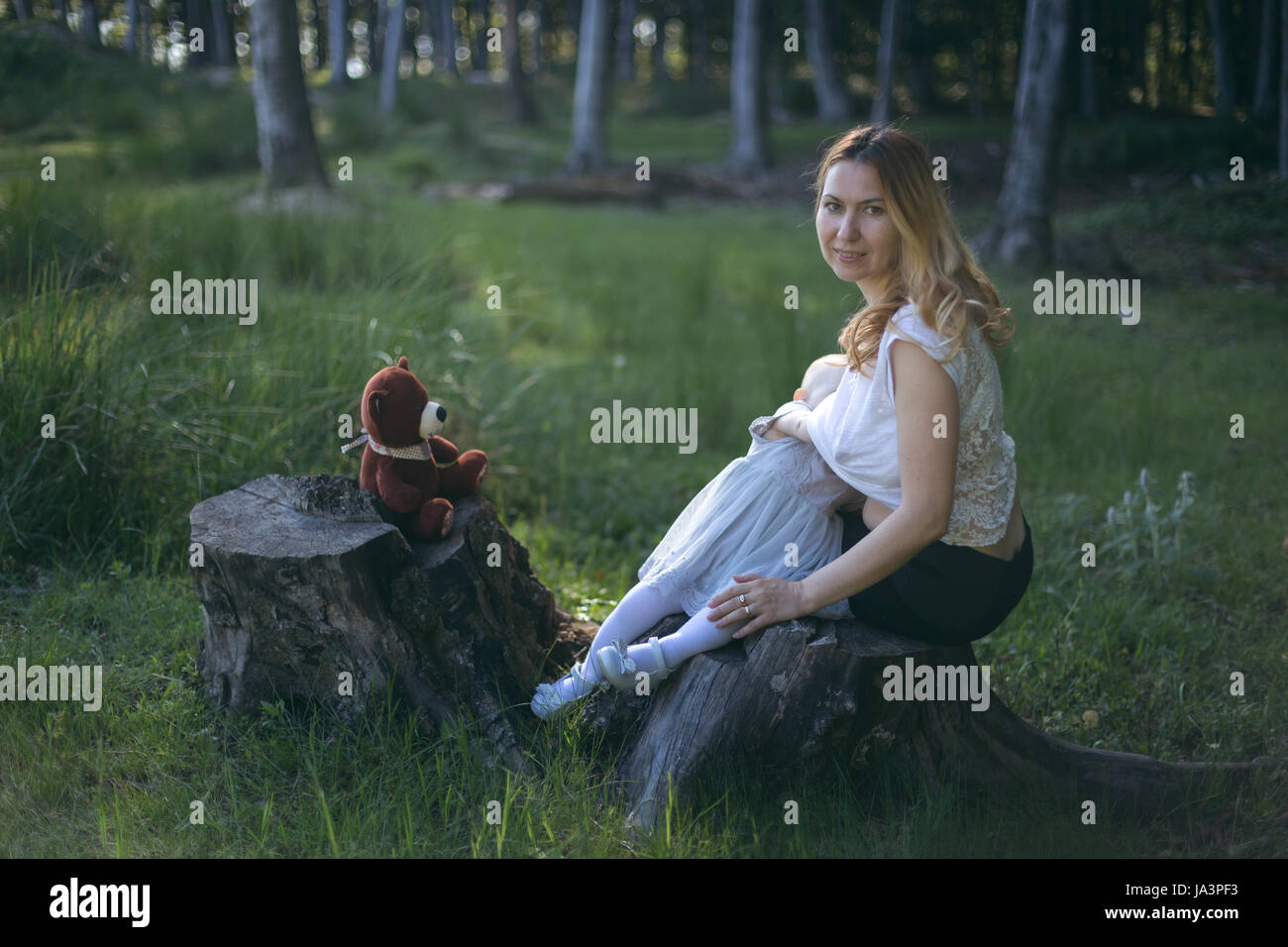 Mother breastfeeding baby girl outside in nature Stock Photo