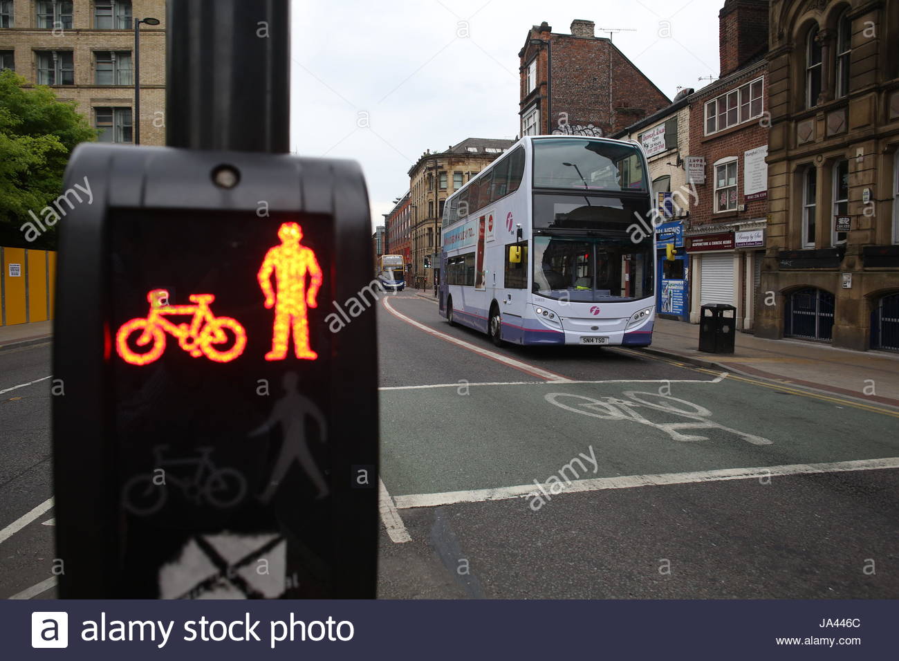 Red light at a pedestrian crossing in Manchester as a city bus approaches. Stock Photo