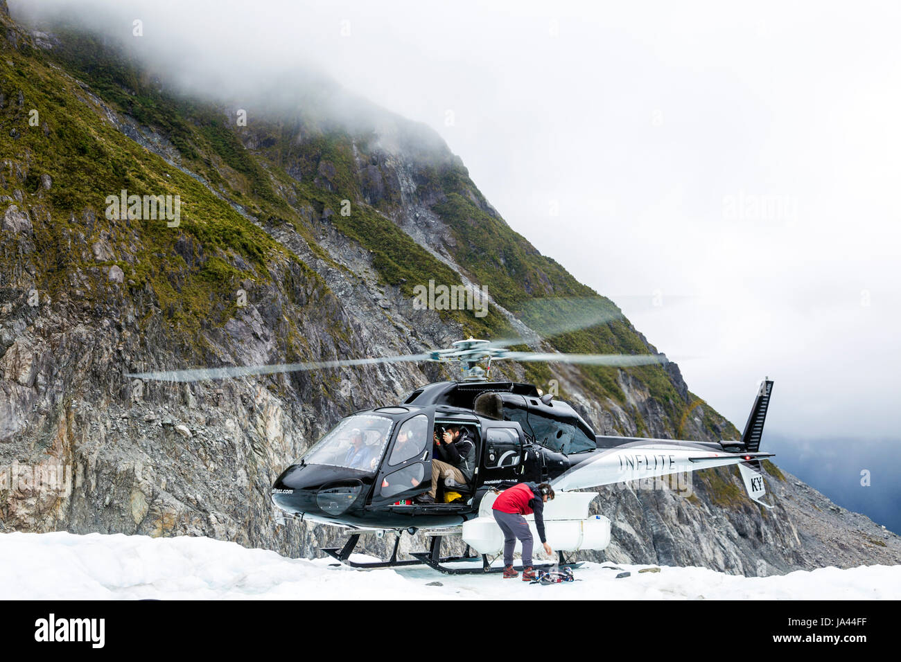 Helicopter dropping people off on a glacier (Fox Glacier, South Island, New Zealand) Stock Photo