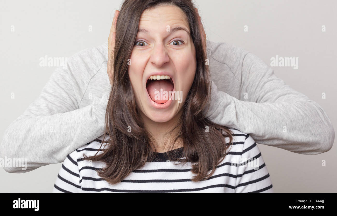 Girl screaming hysterically. Guy plugs her ears Stock Photo
