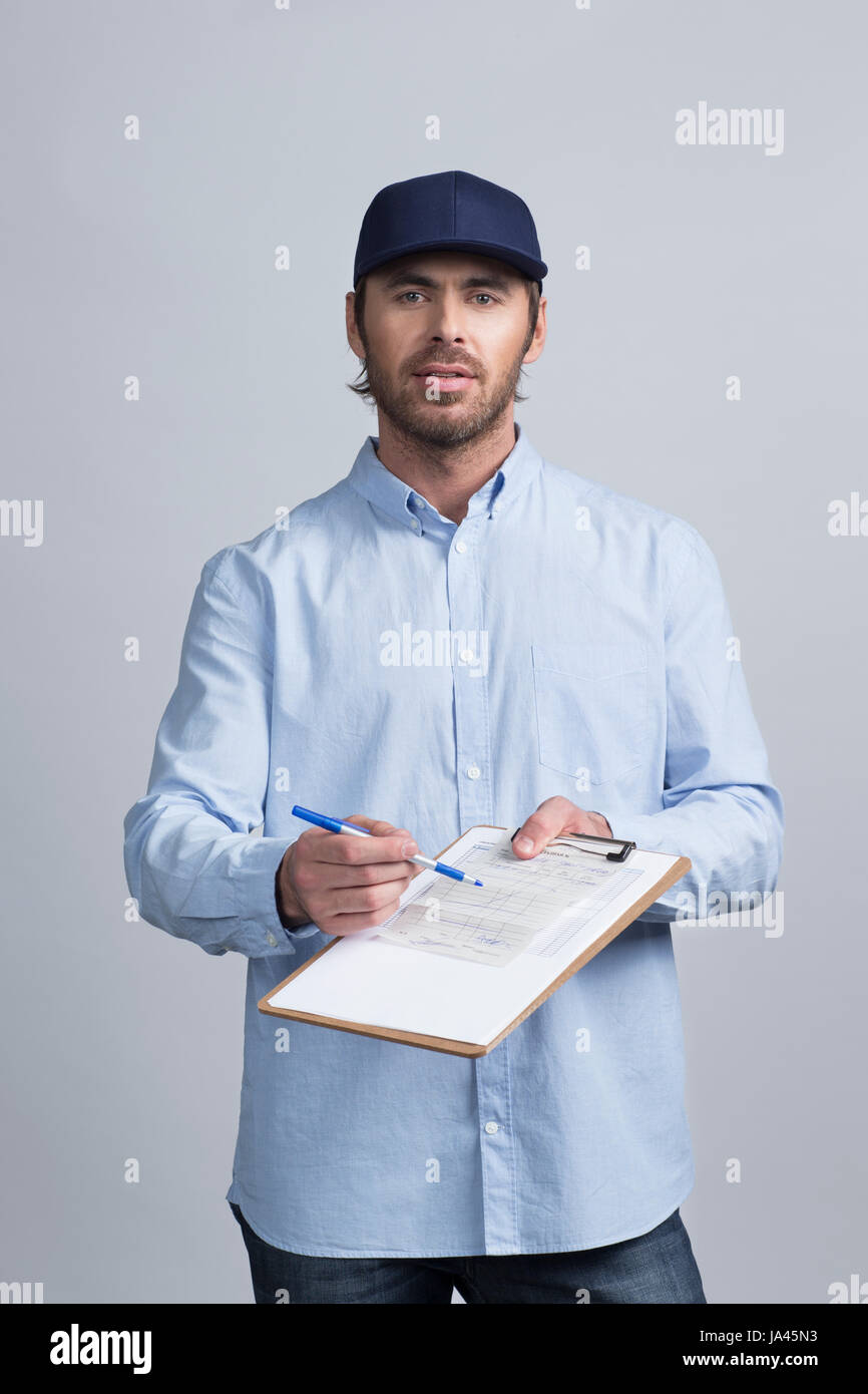 Handsome young delivery man holding document folder ask to sign invoice Stock Photo