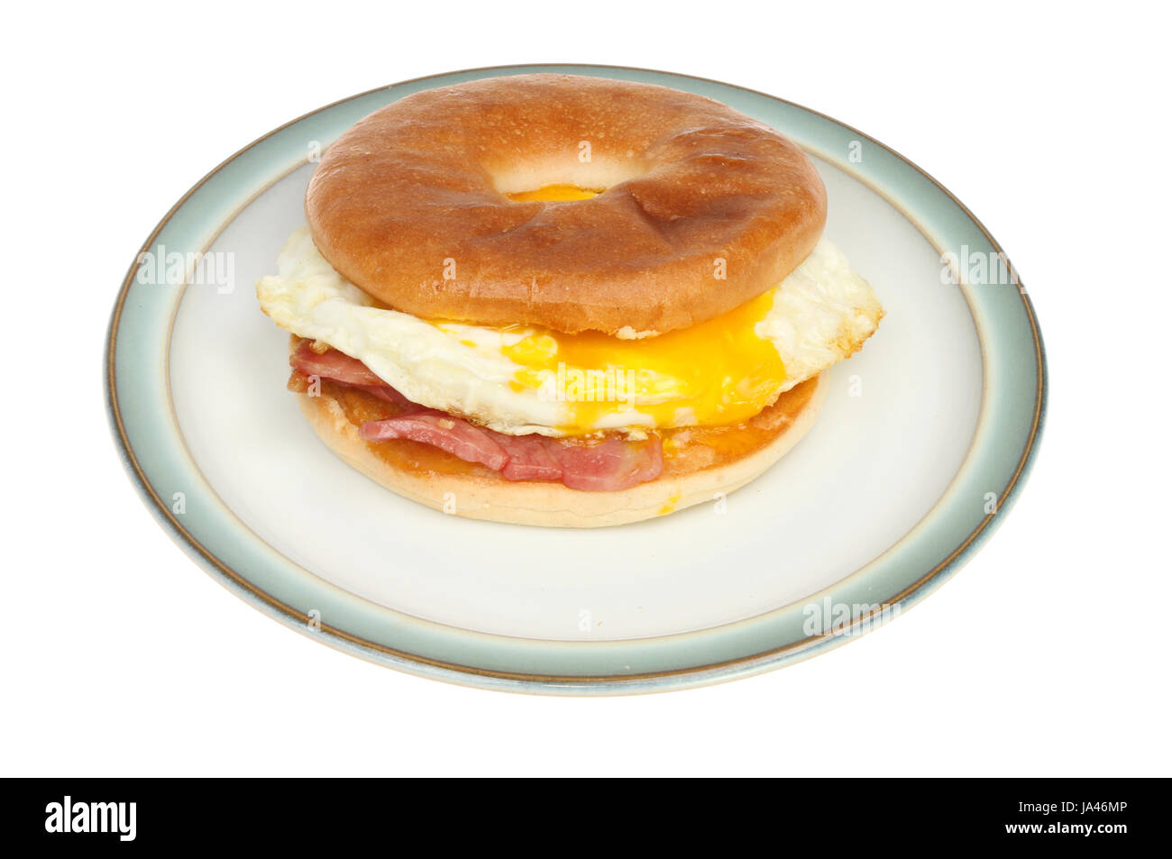 Bacon and fried egg in a toasted bagel on a plate isolated against white Stock Photo