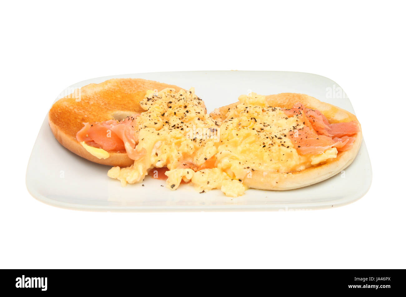 Smoked salmon and scrambled egg on toasted bagels on a plate isolated against white Stock Photo
