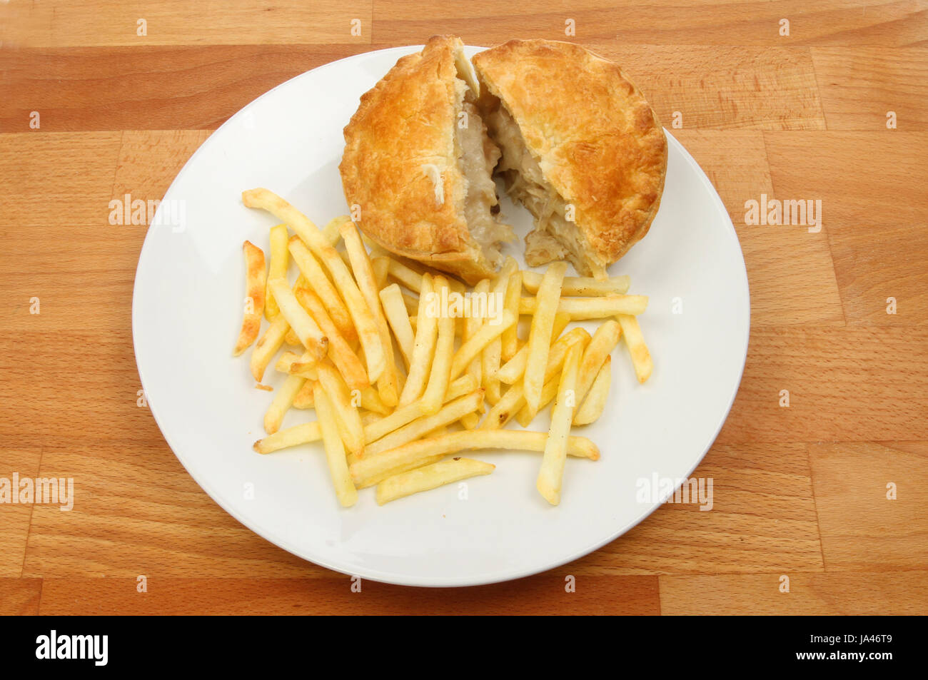 Chicken pie and fries on a plate on a wooden tabletop Stock Photo